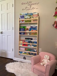 a pink chair sitting in front of a book shelf filled with children's books