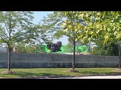 a truck is parked on the side of a road near some trees and grass in front of a concrete wall