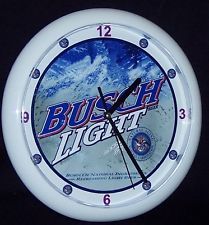 a clock with the words busch light on it's face and an image of mountains in the background