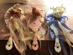 three different colored hair clips with bows and ribbons on top of a wooden table next to a mirror