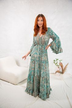 Introducing our stunning Phoebe dress, the perfect addition to any boho-inspired wardrobe. Crafted from high-quality materials, this maxi dress features a chic green allover print that's sure to turn heads. Designed with 3/4 sleeves and a flattering v-neckline, this dress is both feminine and playful. The buttons on the front and drawstring waist allow you to customize the fit to your liking, while the flutter sleeves add a touch of whimsy. Whether you're headed to a summer wedding or a beachside brunch, the Phoebe dress is the perfect choice. Dress it up with heels and statement earrings, or keep it casual with sandals and a sunhat. At Ananda Wild we're committed to creating beautiful, ethically-made pieces that you'll love wearing for years to come. Available in 3 sizes SM Length 150cm W Vintage Boho Print V-neck Dress, Boho Print Free-spirited Dresses, Bohemian V-neck Rayon Maxi Dress, Long Hippie Boho Dress For Spring, Hippie Long Sleeve Vacation Dresses, Spring Boho Print Maxi Dress, Spring Maxi Length Boho Dress, Spring Festival Boho Maxi Dress, Bohemian Long Maxi Dress For Spring