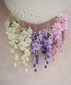 three purple and white flowers hanging from hooks