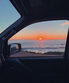 the sun is setting over the ocean as seen from inside a car