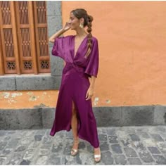 a woman in a purple dress standing on the street