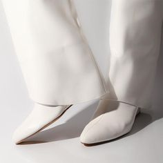 a woman's white shoes and pants are shown from the bottom up on a white surface