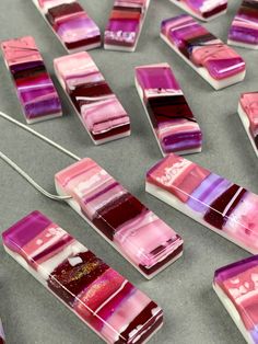 some pink and purple pieces of glass on a table with a silver spoon next to them