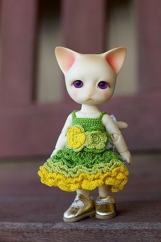 a small doll is wearing a green and yellow dress