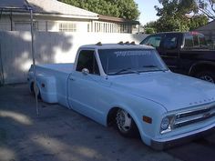 an old white pickup truck parked in a driveway