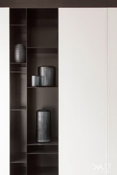 a black and white bookcase with two vases on the shelf next to it