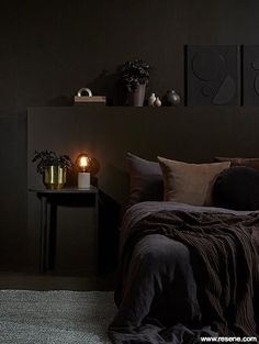 a bed in a bedroom with two candles on the nightstands and pictures above it