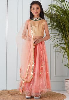 Readymade Net Lehenga in Peach This attire with Shantoon Lining is Enhanced with Fancy Tassels, Sequins Buty Work, Adjustable Drawstrings, Dupatta Enhanced with Sequins Scallop Border. Available with a Sleeveless Textured Brocade Golden Choli Crafted in Round Neck and a Net Dupatta in Peach Do Note: Accessories shown in the image are for presentation purposes only. (Slight variation in actual color vs. image is possible). Eid Saree Set In Peach, Peach Saree Set For Eid, Peach Sets With Dupatta For Diwali, Unstitched Peach Sets With Zari Work, Designer Peach Sets For Diwali, Bollywood Style Peach Traditional Wear For Diwali, Festive Peach Traditional Wear With Zari Work, Peach Bollywood Traditional Wear For Diwali, Traditional Peach Sets For Festive Occasions