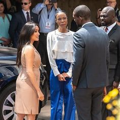 two women are talking to one another in front of a group of men and women