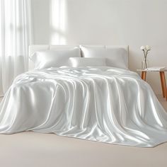 a bed covered in white sheets and pillows