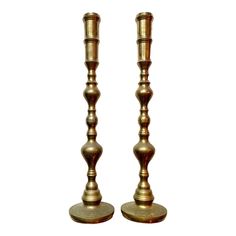 two brass candlesticks are standing next to each other on a white background,