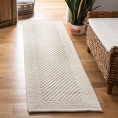 a large white rug sitting on top of a hard wood floor next to a potted plant