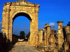 the ruins of an ancient roman city with arches and pillars in the foreground, against a blue sky