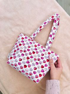 a hand holding a purse with hearts on it