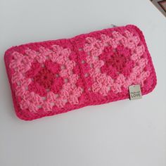 a pink crocheted wallet with a tag on it