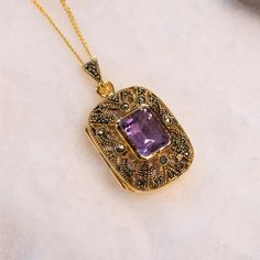 "This genuine amethyst locket necklace features a beautifully-cut real amethyst at its centre. Inspired by a vintage design, this locket opens to reveal two secret photos inside.  DETAILS:  * Our Amethyst Locket necklace is made of 18 carat gold vermeil and is hallmarked by the Edinburgh Assay Office with a full UK hallmark. * The amethyst locket is one of our largest lockets and measures 40mm x 22mm (1.5 inches x 0.9 inches). * This real amethyst gemstone has been carefully cut into facets to s Purple Gemstone Amulet Necklace, Purple Amethyst Amulet Necklaces, Purple Amethyst Amulet Necklace, Purple Amulet Necklaces As Gifts, Purple Amethyst Amulet Jewelry, Purple Amulet Style Jewelry Gift, Purple Amulet Jewelry As Gift, Purple Amulet Jewelry As A Gift, Elegant Purple Locket Jewelry