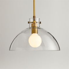 a clear glass and brass pendant light with a white ball hanging from the bottom, on a gray background