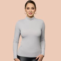 Indulge in the opulent coziness and effortless elegance of our newly updated mock neck. Featuring a sleek and refined neckline, it now comes in 10 stunning hues. Crafted from luxurious Italian 4 way stretch microfiber fabric, it delicately cascades over the figure and eliminates clinginess when layered with other garments. An essential piece for your autumn and winter collection, this top can be worn alone for a striking look or layered under sweaters or jackets. Elegant Mock Neck Top For Winter Layering, Sleek Solid Color High Neck Turtleneck, Sleek High Neck Turtleneck, Elegant Solid Long Sleeve Turtleneck, Elegant Long Sleeve Solid Turtleneck, Elegant Stretch Mock Neck Top For Winter, Elegant Winter Mock Neck Top With Stretch, Elegant High Stretch Tops With Thumbholes, Elegant Second-skin Long Sleeve Tops