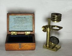 an antique brass and wood box next to a mechanical wind chime on a white background