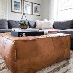 a living room with a couch, ottoman and books on the coffee table in front of it