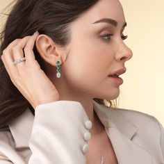 These diamond danglers exude a sense of sophistication and ease. They look relaxed and refined at once with their linear design and subtle movement. Each earring features a trio of round created emerald set in a vertical row and punctuated by a larger oval-cut diamond at the end. This elegant pair is the perfect choice when you want to dress to impress yet still be comfortable. Elegant Diamond Earrings With Timeless Design, Elegant Diamond White Linear Earrings, Elegant Earrings With Timeless Design, Formal Diamond Earrings With Timeless Design, Elegant Oval Diamond White Diamond Earrings, Elegant Oval Diamond White Earrings, Elegant Round Emerald Earrings, Elegant Formal Linear Earrings With Prong Setting, Elegant Emerald Earrings For Formal Occasions