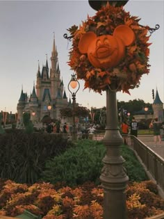 an orange pumpkin hanging from the top of a lamp post in front of a castle