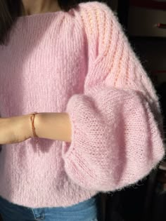 a woman wearing a pink sweater and bracelet