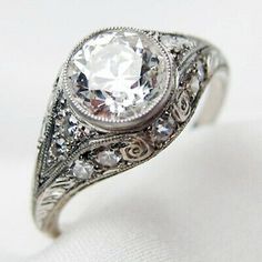 an antique style diamond ring with filigrees on the band and center stone