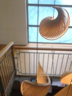 three wooden chairs hanging from the ceiling in front of a window with a skylight above them