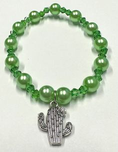 Beautiful handmade green cactus bracelet. Will look stunning on you. Wear it whenever you want. Can be for all. Girls, teens, or women.  *Handmade *Made with elastic string *Green crystal beads - Crystal beads size: 4mm *Pearl bead size: 8mm *Cactus with flower on top charm Cute Green Stretch Bracelet With Round Beads, Cute Green Round Beads Stretch Bracelet, Cute Adjustable Green Beaded Bracelets, Cute Handmade Green Stretch Bracelet, Handmade Cute Green Stretch Bracelet, Green Beaded Stretch Bracelet, Cute Green Handmade Stretch Bracelet, Cute Green Round Bead Jewelry, Trendy Green Hypoallergenic Beaded Bracelets