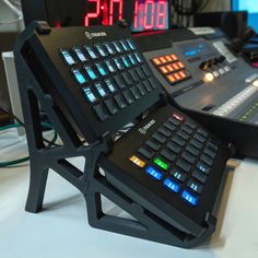 a computer keyboard sitting on top of a stand next to a clock and other electronic equipment