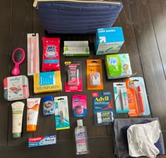 the contents of a travel bag laid out on top of a wooden floor next to a blue purse