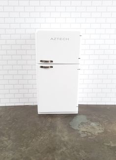 a white refrigerator freezer sitting on top of a cement floor