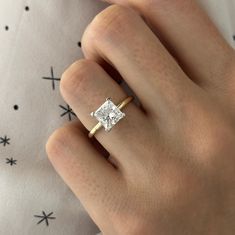 a woman's hand with a diamond ring on top of her left hand,