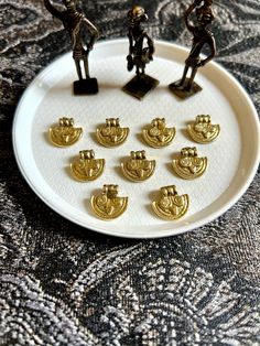 several small figurines sitting on top of a white plate with gold trimmings