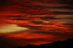 the sky is red and orange as it looks like clouds are coming up from the ground