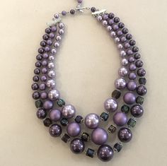 Fantastic pearl necklace with graduated round beads in various shades of purple. The shortest row is designed with lavender pearls, the middle row is designed with matte purple beads and the longest row is designed with a deeper purple pearlized color. There are faceted 12 amethyst crystals manipulated between the pearls in the front of the necklace. The beads are graduated in size and the colors are tonal that create a very fashionable look. Elegant Purple Beaded Necklace With Round Beads, Purple Beaded Pearl Necklace, Purple Pearl Necklaces With Round Beads, Adjustable Purple Beaded Pearl Necklace, Adjustable Purple Pearl Necklace With Round Beads, Adjustable Beaded Purple Pearl Necklace, Luxury Purple Pearl Necklaces, Purple Single Strand Pearl Necklace, Purple Pearl Single Strand Necklace