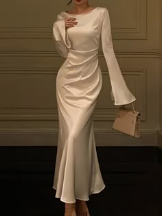 Experience the jazz-age revival with this elegantly designed white gown, complete with bell sleeves that add a vintage touch to a modern silhouette. The sleek bodice highlights the natural waistline, while the gently flaring skirt creates a flowing movement as you walk. Made from premium fabric that hugs the body while allowing for a full range of motion, this dress combines the best of both comfort and style. It’s a contemporary take on classic glamour, perfect for evenings where making a grace Floor Length Dresses With Sleeves, Elegant Dresses Everyday, Classy Prom Dresses Sleeves, Modern Chic Clothing Style, Pink Satin Dress With Sleeves, Events Dresses Elegant, Bell Sleeve Gown, Full Sleeve Gown Designs, Sliky Long Dresses