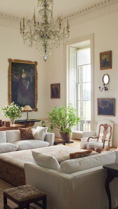 a living room filled with lots of furniture and a chandelier hanging from the ceiling