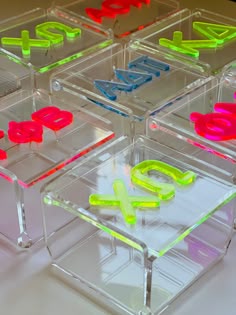 four clear acrylic boxes with neon colored letters on them and the word love spelled inside