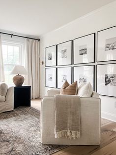 a living room filled with furniture and framed pictures on the wall above an area rug