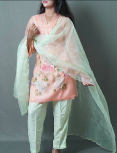 3 pc suit consisting of peach kurta, light green pant, and light green chiffon dupatta Delicately hand painted organza kurta with beautifully designed floral patterns on daman and sleeves Kurta styled with three quarter sleeves and heavy tassel hanging pearl lace on neck Duppata enhanced with curved golden pippin on all borders Number of components sold: 4 (Kurta comes with inner) Measurement in the size guide are all body measurements Spring Green Traditional Wear With Gota Work, Green Traditional Wear With Gota Work For Spring, Spring Anarkali Tissue Silk Kurta, Traditional Tissue Silk Sets For Spring, Spring Green Sets With Gota Work, Spring Silk Sharara With Dupatta, Spring Chanderi Sharara, Spring Semi-stitched Salwar Kameez With Gota Work, Traditional Palazzo Set With Sheer Dupatta For Spring