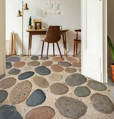 a chair sitting on top of a stone floor next to a wooden table and desk