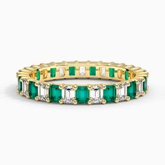 an emerald and white diamond ring in yellow gold with diamonds on the sides, set against a