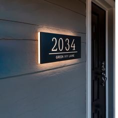 a black and white house number sign on the side of a building with lights above it