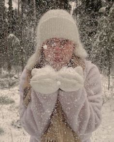 a woman standing in the snow with her hands covering her face