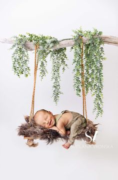 a baby is sleeping on a swing with some plants hanging from it's sides